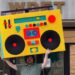 In The Groove host Ryan Patrick Hooper holds Detroit's largest boombox — designed by Detroit artist Matthew Holman — outside of WDET Studios during the 2025 spring fundraiser.