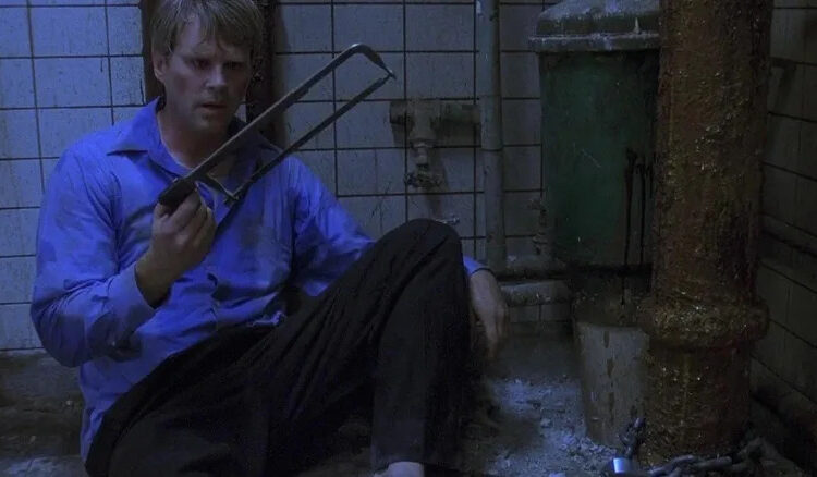 Lawrence holding a saw in Saw