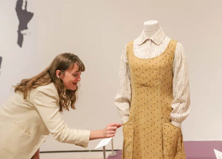 Elyse Gerstenecker, curator of decorative Arts, carefully pushes in a pin that is sticking out without touching the costume during the Art of the Character exhibit, featuring highlights from Glenn Close's costume collection on Thursday, October 9, 2025 at the Jepson Center for the Arts.