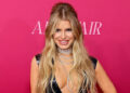 Jessica Simpson smiling on red carpet in black latex dress with plunging neckline