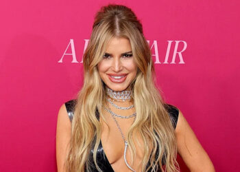 Jessica Simpson smiling on red carpet in black latex dress with plunging neckline