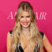 Jessica Simpson smiling on red carpet in black latex dress with plunging neckline