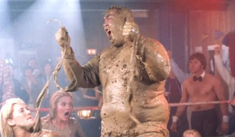 John Candy turns the table on his mud wrestling opponents as Dewey "Ox" Oxberger in Stripes