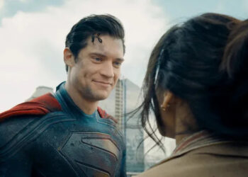 David Corenswet as Superman in Superman, dirty but smiling at a woman he just saved