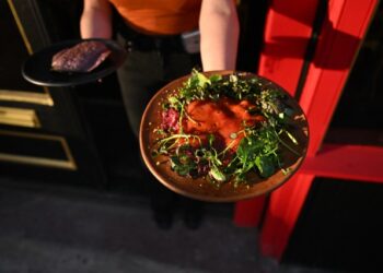A server presents the Sabana de Atún dish at Malinche Audiobar in downtown Denver., on Oct. 16, 2025. (Photo by RJ Sangosti/The Denver Post)
