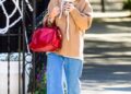 Katie Holmes carrying her Metier red bag and wearing wide-leg jeans and Autry sneakers