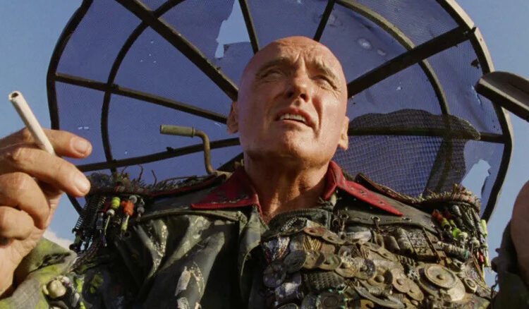 Dennis Hopper as The Deacon holding a cigarette in Waterworld