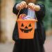 a child holds a trick or treating bucket