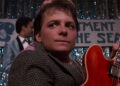 A close up of Michael J. Fox holding the red guitar in Back to the Future.