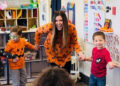 Children in halloween clothes dancing with an instructor.