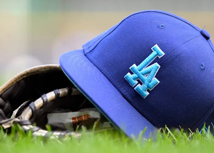 A Los Angeles Dodgers hat sits on a a baseball glove during a MLB game between the Milwaukee Brewers and Los Angeles Dodgers on August 12, 2024, at American Family Field in Milwaukee, WI.