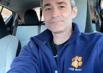 William Arnold, a music teacher, wears a blue fleece with "PTHS MUSIC" and an "I GOT THE COVID-19 VACCINE" sticker.