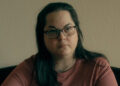 Kerri Rawson sitting on her bed.