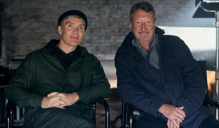 Cillian Murphy as Thomas Shelby sitting next to creator Steven Knight in a behind-the-scenes picture for Peaky Blinders