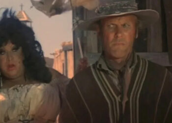 Divine as Rosie Velez and Tab Hunter as Abel Wood standing side-by-side in a western town in Lust in the Dust