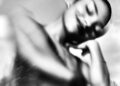 A blurry black and white photo of a smiling woman leaning on her hand.