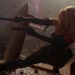 Barb firing two guns from behind a table in Barb Wire