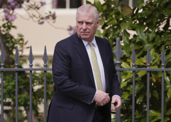 Prince Andrew, the Duke of York, looking over his shoulder while wearing a suit.