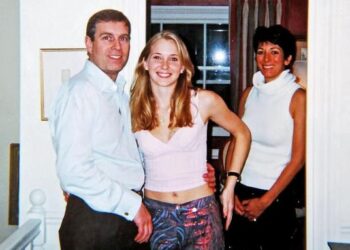 A man and two women stand in a house looking at the camera.