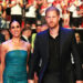 Meghan Markle and Prince Harry holding hands and walking together as a crowd cheers behind them.
