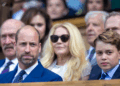 Prince George and Prince William sitting in the stands wearing blue suits at Wimbledon