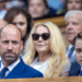 Prince George and Prince William sitting in the stands wearing blue suits at Wimbledon