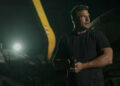 alt="Reacher holds a gun and looks to his side in Reacher season 3"