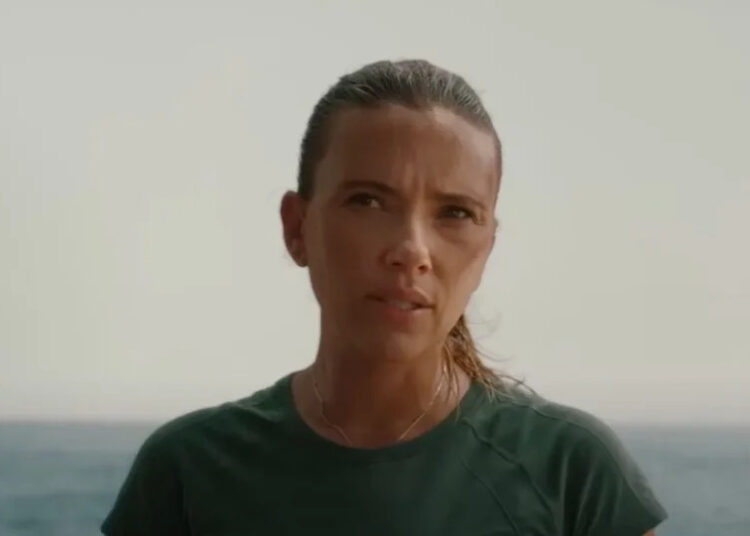 Scarlett Johansson looking skeptically at someone off screen in Jurassic World Rebirth near a large body of water.