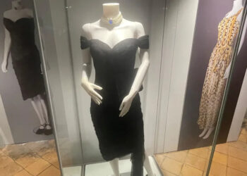 A mannequin in a glass display cabinet wearing a black dress