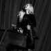 Reneé Rapp sits smiling atop a piano while performing