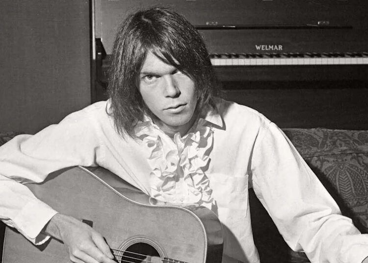 Neil Young playing an acoustic guitar.