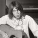 Neil Young playing an acoustic guitar.