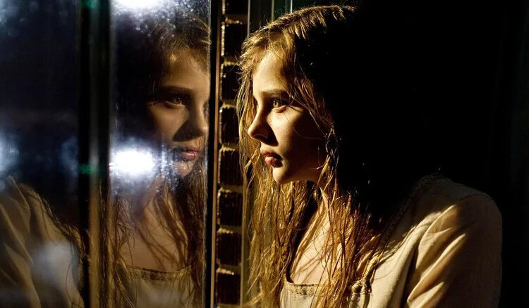Abby stares through her reflection in Let Me In