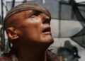 Dennis Hopper as Deacon staring up in disbelief in Waterworld