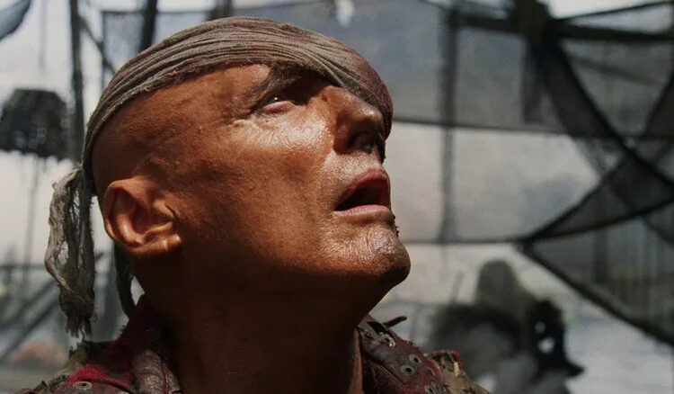 Dennis Hopper as Deacon staring up in disbelief in Waterworld