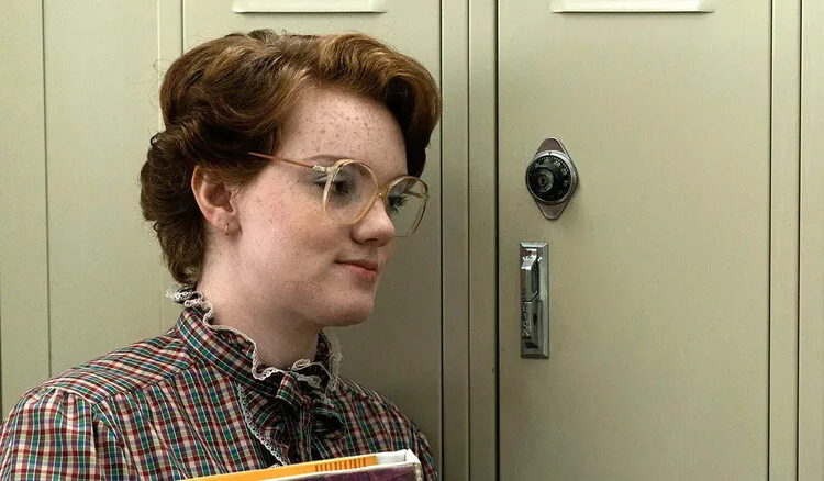 Shannon Purser as Barb standing in front of her locker in Stranger Things season 1