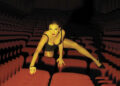Taylor Swift crawling over theater chairs in the trailer for The Official Release Party of a Showgirl