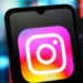 Smartphone displaying the Instagram logo, with a colorful blurred background.