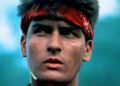 Chris Taylor wearing a red headband in the jungle in Platoon