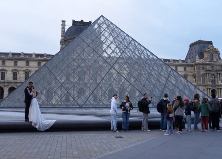 A wedding couple hugs as visitors queue to enter the Louvre museum three days after historic jewels were stolen in a daring daylight heist, on October 22, in Paris. Photo: AP Photo