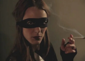 A masked woman smoking a cigarette in 50 Kisses