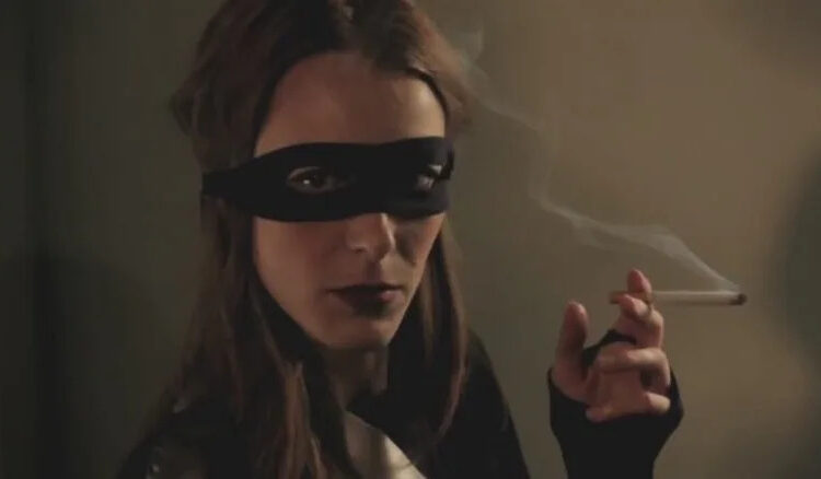 A masked woman smoking a cigarette in 50 Kisses
