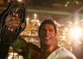 Dwayne Johnson as Mark Kerr holding up a championship belt in The Smashing Machine
