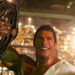 Dwayne Johnson as Mark Kerr holding up a championship belt in The Smashing Machine