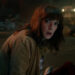 Winona Ryder as Joyce Byers crouched in the street with a look of horror on her face in Stranger Things