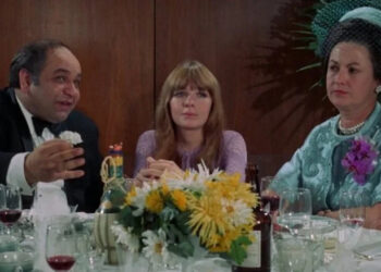 Joan sitting with two older people at a wedding in Lovers and Other Strangers