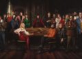 The cast of The Celebrity Traitors stand around a circular table wearing poker faces whilst the show's host, Claudia Winkleman, stands centre.