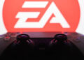 Electronic Arts logo displayed on a laptop screen and DualSense controller are seen in this illustration photo taken in Krakow, Poland on September 29, 2025.