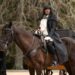 Claudia Winkleman sits on a horse wearing black mourning clothes as part of a funeral procession.