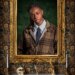 Singer Cat Burns, a contestant on "The Celebrity Traitors," dressed in a plaid jacket, white shirt, and navy tie, framed by a gold ornate picture frame with a floral tapestry background.